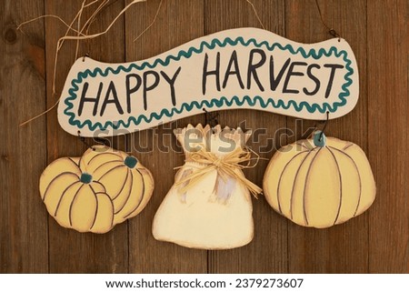 Happy Harvest sign with pumpkins on weathered wood