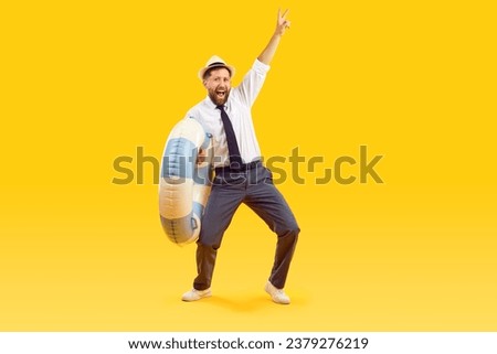 Joyful male office worker is happy to finally go on long-awaited summer vacation. Excited funny businessman in formal wear holding swimming circle and showing V sign isolated on orange background.