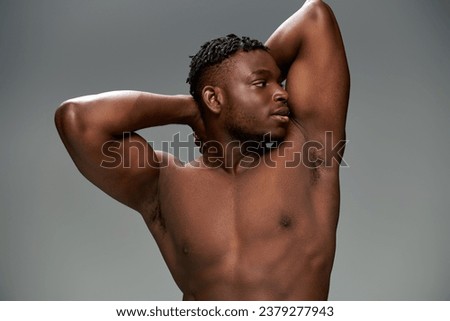 sportive and shirtless african american man with muscular body posing with hands behind head on grey