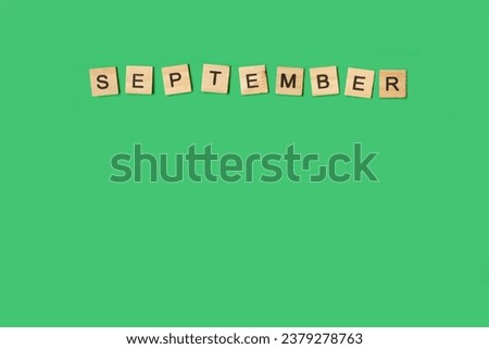September word made with wooden letter blocks on a green background with copy space