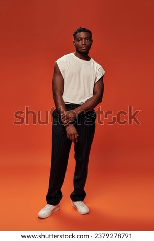 full length of african american fashion model in stylish street wear on red and orange backdrop