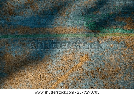 Abstract grunge background. Worn chipboard texture, painted blue and outdated in time, close-up. Rays of sun and shadows from foliage
