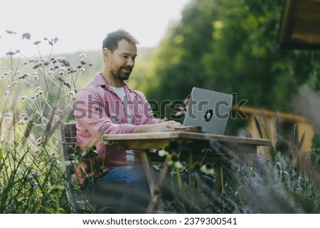 Low angle shot of man working outdoors in the garden, with laptop on legs. Businessman working remotely from homeoffice, thinking about new business or creative idea.