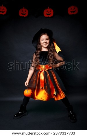 Young kid girl in Halloween witch costume goes trick or treating on black background