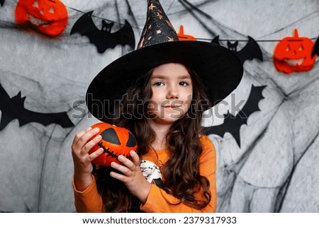 Happy halloween. Close-up of cute little kid girl in witch costume with carving pumpkin