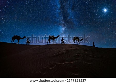 Christmas Jesus birth concept - Adoration of the Magi, Three Wise Men, Three Kings, and the Three biblical Magi with camel silhouettes journeying in sand dunes of desert follow Bethlehem star at night Royalty-Free Stock Photo #2379328537