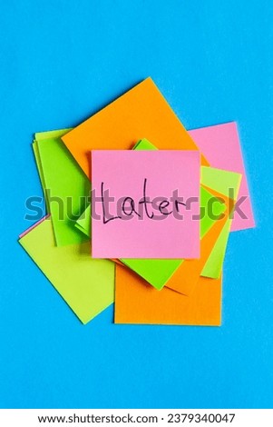 Later written on sticky note, colorful paper reminders on a blue background, top view.