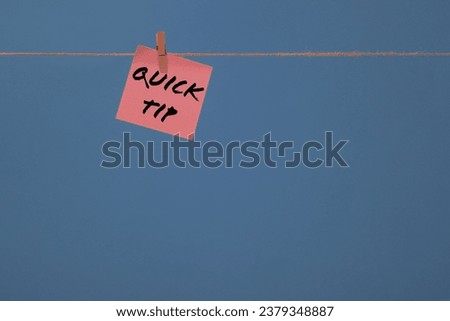 Words QUICK TIP written on pink sticky note memo and isolated on blue background with lot of space for copy text.