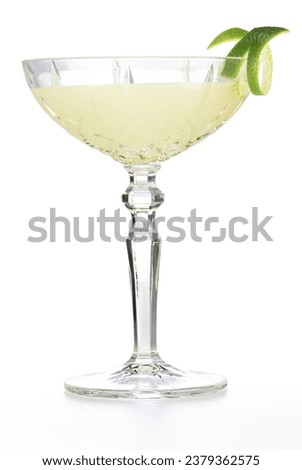 Classic daiquiri cocktail in glass cup garnished with lime zest isolated on white background.