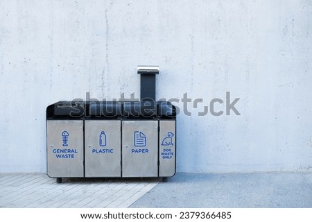 4 metal stainless steel recycle bins and trash bin with icons against grey wall. Keep environment clean design concept image with empty space for text. High quality photo.