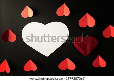 White hearts and red hearts made of paper are placed on a black background.