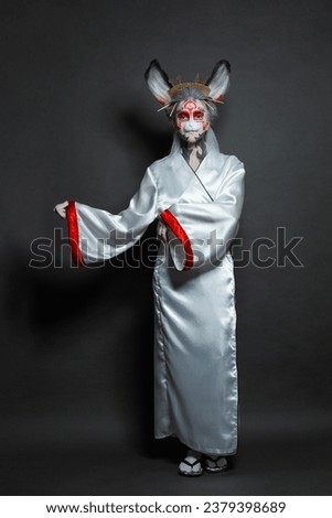 Pretty fashion model woman wearing Halloween or carnival costume and kimono standing on black background, studio portrait
