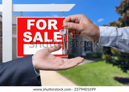 Real Estate Agent Handing Over the House Keys in Front of a Beautiful New Home and For Sale Real Estate Sign