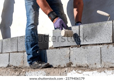 A builder lays an aerated concrete block on a wall Royalty-Free Stock Photo #2379406179