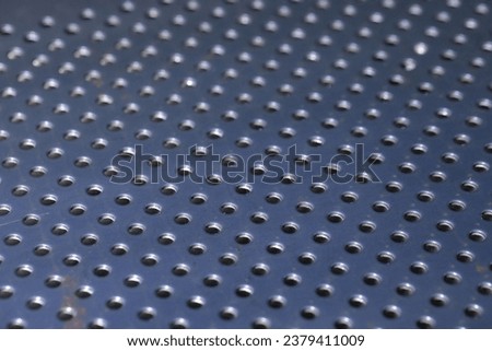 Steel plate with many circular holes drilled.