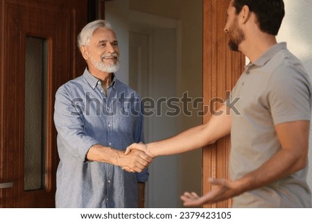 Friendly relationship with neighbours. Happy men shaking hands near house outdoors Royalty-Free Stock Photo #2379423105