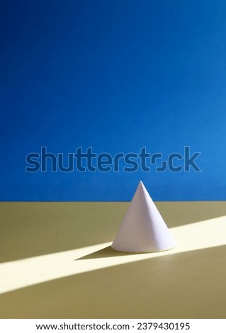a cone and its shadow on yellow and blue background