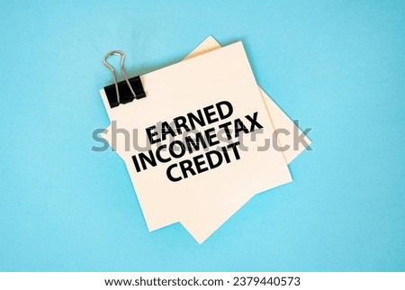 Text EARNED INCOME TAX CREDIT on sticky notes with copy space and paper clip isolated on red background. Finance and economics concept. Royalty-Free Stock Photo #2379440573