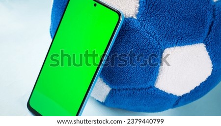 Smartphone with green screen next to soccer ball