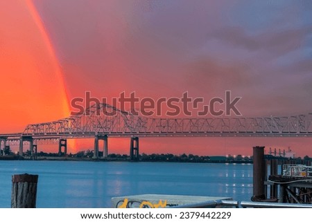 a gorgeous summer landscape along the Mississippi River with the Crescent City Connection bridge over the water with powerful clouds at sunset and a rainbow in New Orleans Louisiana USA