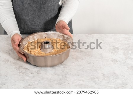 Filling metal bundt cake pan with cake butter to bake carrot bundt cake with cream cheese frosting. Royalty-Free Stock Photo #2379452905