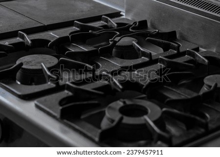 Cast iron gas hob, detail of a stove part with grates on top and nozzle for gas visible. Gray cold picture of a cooking top.