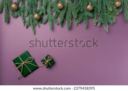 Christmas flat lay on a purple background with fir branch, balls and box