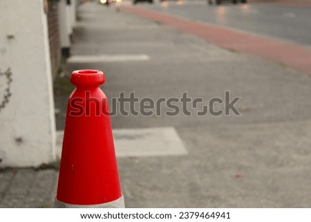 A photo of the top of an orange traffic cone on a path. 