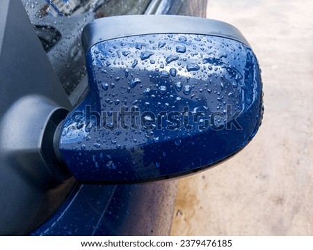 Raindrops on side mirror of blue painted car. Beautiful rain bubbles on the car. Royalty-Free Stock Photo #2379476185
