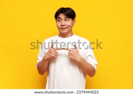 modest young asian guy in white t-shirt feeling shy on yellow isolated background, confused korean man feeling embarrassed and feeling uncomfortable Royalty-Free Stock Photo #2379494023