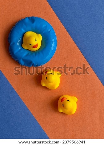 A bright picture of children's toys of a yellow duck on an orange background with blue fields