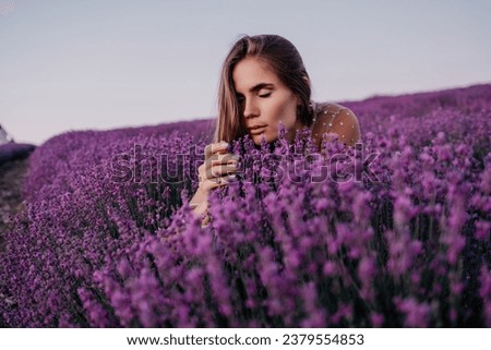 Woman lavender field. Happy carefree woman in beige dress and hat with large brim smelling a blooming lavender on sunset. Perfect for inspirational and warm concepts in travel and wanderlust. Close up Royalty-Free Stock Photo #2379554853