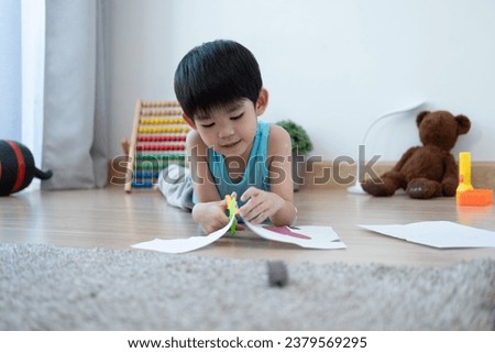 Asian boy using scissors to cut paper along lines Learning outside the classroom

 Royalty-Free Stock Photo #2379569295