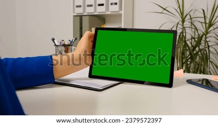Close up chorma key horizontal tablet screen used by female worker. Woman using tablet sitting at desk browsing Internet.