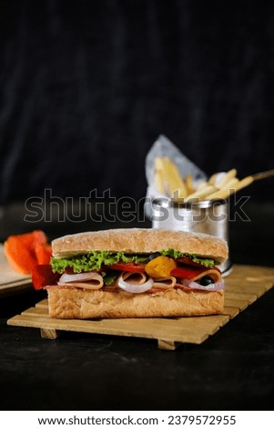 Ciabatta Smoked Ham Sandwich isolated on wooden with mayonnaise dip and french fries bucket board side view of italian fast food on grey background