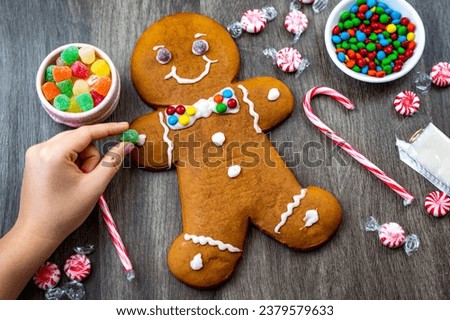 The girl decorates the Gingerbread Man. Christmas time. Royalty-Free Stock Photo #2379579633