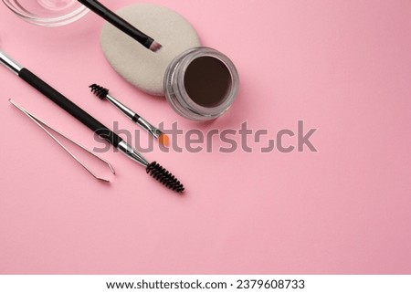 Eyebrow pomade with henna effect and professional tools on pink background, flat lay. Space for text