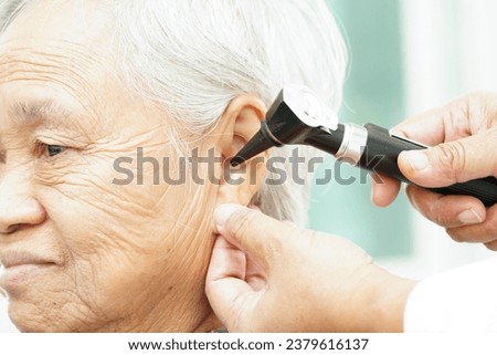 Otolaryngologist or ENT physician doctor examining senior patient ear with otoscope, hearing loss problem. 