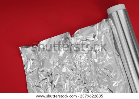 Roll of aluminum foil on red background, top view. Space for text Royalty-Free Stock Photo #2379622835