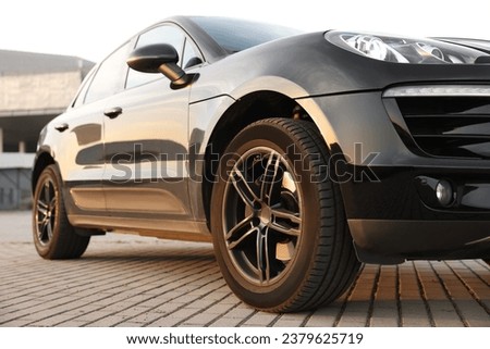 Modern black car parked on stone pavement outdoors