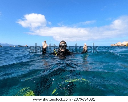 Diver woman floating on the surface of the water making the "Ok" sign with both hands to signal that everything is correct. Security control, communication between divers. Water sport concept Royalty-Free Stock Photo #2379634081