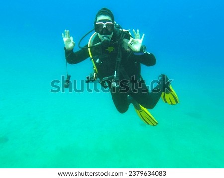 Woman scuba diver alone showing "Ok" signal underwater, "I am Ok", safety check, underwater communication while diving. Water sport concept Royalty-Free Stock Photo #2379634083