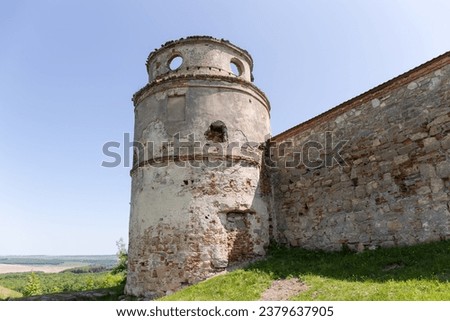 Former fortified Dominican Monastery 15th century, outside view of the round corner defensive tower and part of wall against the clear sky, Pidkamin village, Ukraine 
