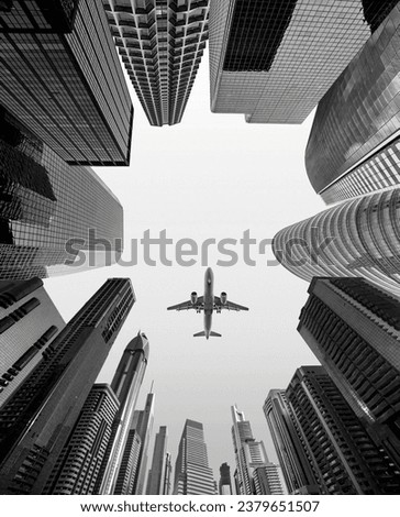 Airplane flying over business skyscrapers of financial center. Travel, economy, cargo, transportation concept. Low wide angle perspective view, black and white photography