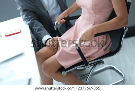Hand of male leader on leg of female subordinate workplace. Harassment at work concept