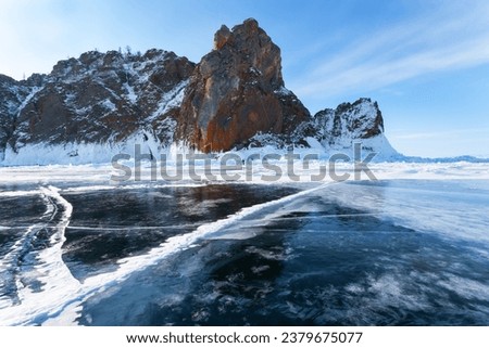 Baikal Lake on February. Famous natural landmark of Olkhon Island, Khoboy rock, is covered with thick layer of ice crust. Tourists love to travel across ice and take pictures on ice floes. Winter view