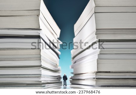 Miniature businessman lost into a huge pile of paperwork Royalty-Free Stock Photo #237968476