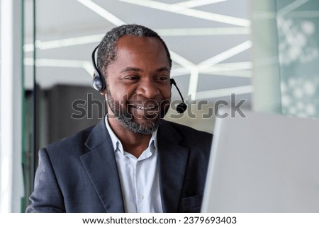 Mature experienced man in business suit with headset phone, working inside office with laptop, businessman online customer support worker, consulting customers remotely, selling in telestore. Royalty-Free Stock Photo #2379693403