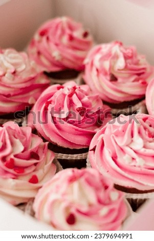Pink cupcakes with cream in a white box.