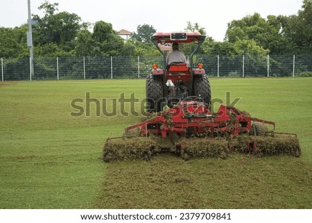 Lawn care - verticut, thatch the grass, aerating and scarifying the lawn in the sports field. Improving the quality of the lawn by removing old grass and moss Royalty-Free Stock Photo #2379709841